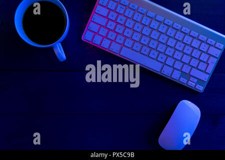 Computer keyboard on wood office desk table at night with lights Stock Photo