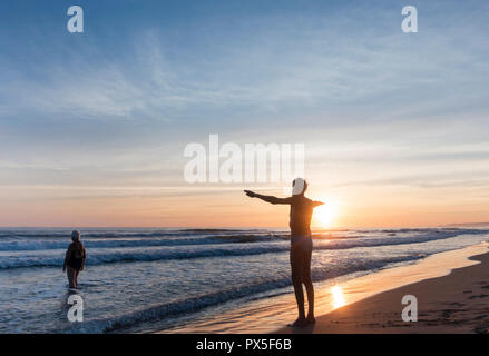 Elderly man stretching before swim on beach at sunrise. Stock Photo