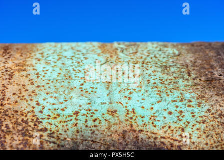 Close detail of metallic rust with green paint background against a blue sky. Stock Photo