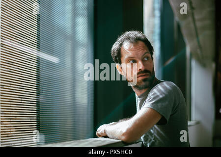 caucasian man looking over his shoulder with a concerned look Stock Photo