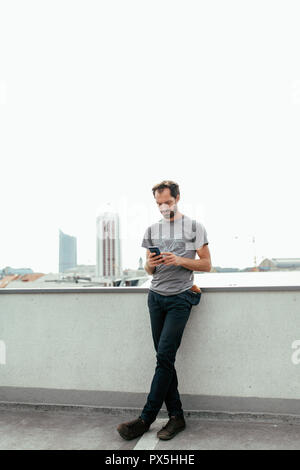 vertical photo of Young bearded man communicating via his smartphone Stock Photo