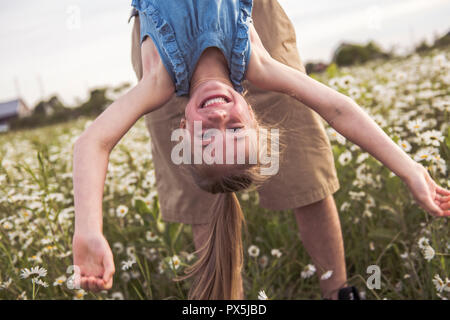 A Portrait of Happy little blond girl playing upside down Stock Photo