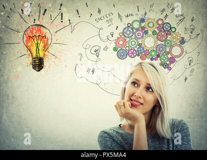 Young woman hand under chin and colorful gear brain above head. Pensive emotion, positive thinking with arrows and curves going to a colorful light bu Stock Photo