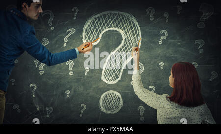 Man and woman perplexity sharing thoughts together have the same common question, drawing interrogation mark on blackboard. Business partnership and t Stock Photo