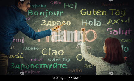 Man and woman together drawing word hello in different languages and colors on blackboard. Opportunity for learning many languages for students. Busin