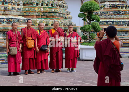 Visiting Tibetan monks taking snapshots in front of chedis (stupas) at Wat Po, Bangkok, Thailand Stock Photo