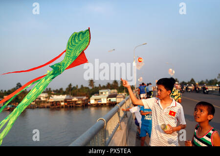Vietnamese children flying kites on Cai Be bridge. Stock Photo
