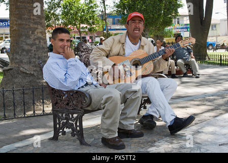 Man playing guitar and friend at Parque Hidalgo, Tecate, Baja California, Mexico Stock Photo