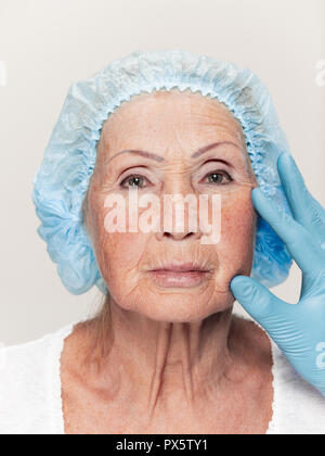 The surgeon doing skin check on mid age woman before plastic surgery. Senior female model. plastic surgery, lifting, aging concept Stock Photo