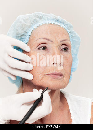 The surgeon doing skin check on mid age woman before plastic surgery. Senior female model. plastic surgery, lifting, aging concept Stock Photo