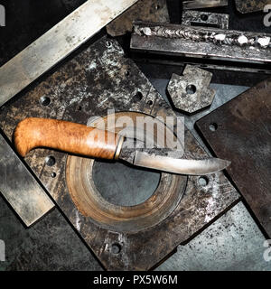 Metalworking still life - top view of forged knife with wooden handle on metal workbench in turnery workshop Stock Photo