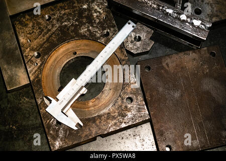 Metalworking still life - top view of callipers on metal workbench in turnery workshop in warm yellow light Stock Photo