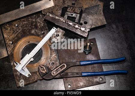 Metalworking still life - top view of calipers and adjustable pliers on metal workbench in turnery workshop in cold blue light Stock Photo