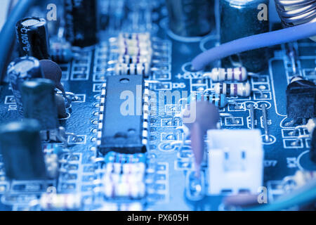 Microchip, capacitors, resistors on a blue computer board close-up. Industrial background. Stock Photo
