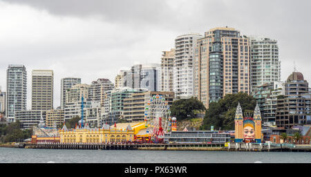 Luna Park amusement park on Milsons Point on the shore of Sydney Harbour and cityscape and skyline of North Sydney NSW Australia. Stock Photo