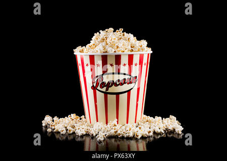 Retro popcorn box full and spilled popcorn isolated on black background in studio. Movie and cinema concept Stock Photo