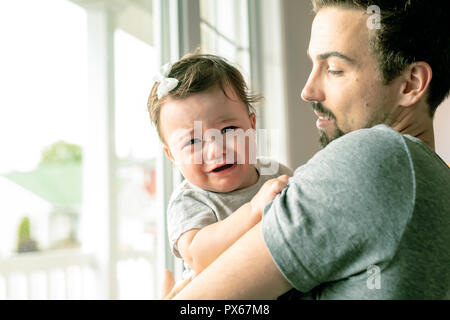 A Father holding little girl close to the window, unhappy girl cry Stock Photo