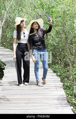 Young asian women walking and selfie on the wooden bridge Stock Photo