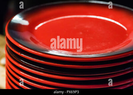 Stack of colorful red ceramics plates on dark background Stock Photo