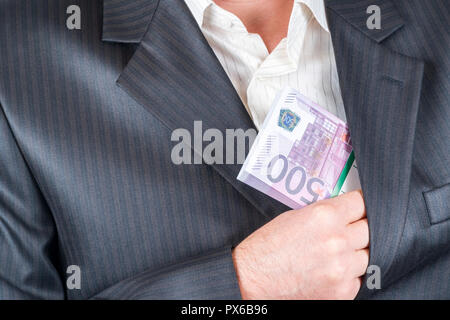 male hand hiding a bundle of money with par value of five hundred euros in the inside pocket of his jacket Stock Photo