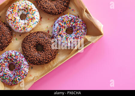 Delicious glazed donuts in box on pink surface. Flat lay minimalist food art background. Top view. Stock Photo