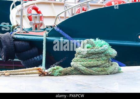 Rolled green nautical rope against of the moored yacht. Stock Photo