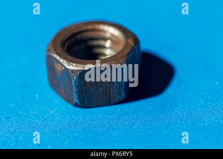 old rusty nut isolated on light blue background Stock Photo