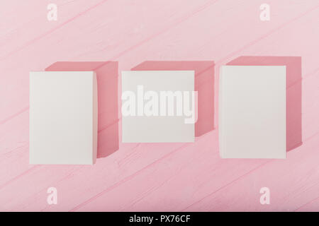 Top view three empty white boxes on pink wooden table. Flat lay composition set of rectangular blank gifts. Stock Photo