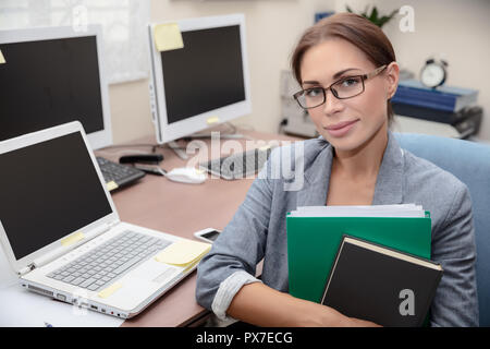 Portrait of a nice office worker, pretty female with folders in hands at work, successful business people life, young woman entrepreneur Stock Photo