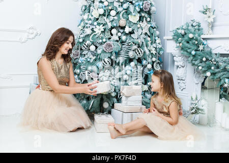 Mother gives Christmas gift to his little son for a New Year. Mom and son  opening Christmas presents Stock Photo - Alamy