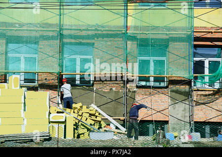 Construction workers plaster the facade of the building. Restoration of the house. Stock Photo
