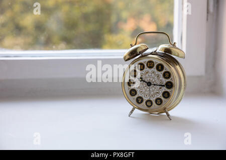 Time management. Golden alarm clock in the morning, blur glass window background, Stock Photo
