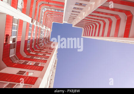 View of a residential building from the bottom up. White house with red balconies in a warm sunny day