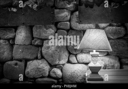 Stone wall illuminated by stylish lamp on wooden table Stock Photo