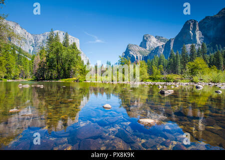 Classic view of scenic Yosemite Valley with famous El Capitan rock climbing summit and idyllic Merced river on a sunny day with blue sky and clouds Stock Photo