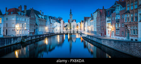 Beautiful panoramic view of famous Spiegelrei canal with famous Poortersloge and Jan van Eyck square in the background illuminated during blue hour Stock Photo