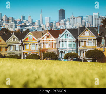 Classic postcard view of famous Painted Ladies, a row of colorful Victorian houses located at Alamo Square, with the skyline of San Francisco in the b Stock Photo