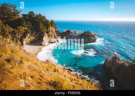 Classic postcard view of famous McWay Falls in scenic golden evening light at sunset on a beautiful sunny day with blue sky in summer, California, USA Stock Photo