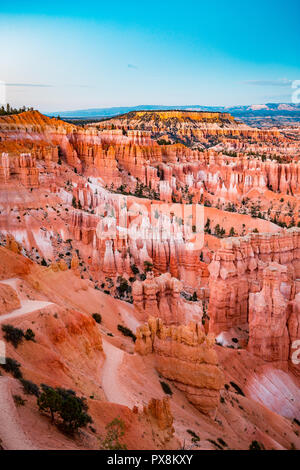 Classic view of Bryce Canyon National Park in beautiful golden evening light at sunset with blue sky and dramatic clouds seen from famous Sunset Point Stock Photo