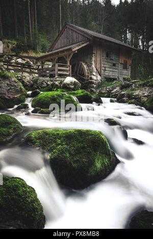 Idyllic long exposure view of an old abandoned mill with mossy rocks lying in beautiful riverbed in a mystic forest on a cloudy moody day in springtim Stock Photo