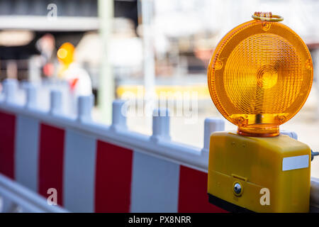 Construction site and safety. Street barricade with warning signal lamp on a road, blur site background Stock Photo