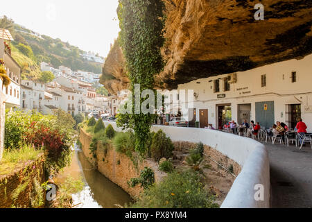 Buildings constructed under big rock natural formations in Setenil de las Bodegas. Houses and shops are carved into the rock, providing natural coolin Stock Photo