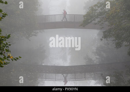 Chippenham; UK; 20th October; 2018. As many parts of the UK wake to a cold foggy start, a man is pictured walking across a bridge over the river Avon in Chippenham; Wiltshire thats shrouded in fog. Credit: Lynchpics/Alamy Live News Stock Photo