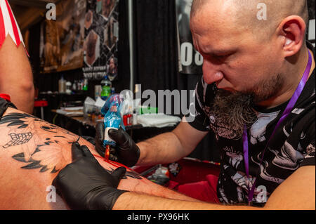 Skibbereen, West Cork, Ireland. 20th Oct, 2018. Tattooist Andrew Chesiak of Clonmel Ink tattoos Razvan Lazar of Clonmel during the tattoo show. The show has been attended by many tattooists from across Ireland and the North. The event finishes tomorrow. Credit: Andy Gibson/Alamy Live News. Stock Photo