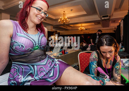 Skibbereen, West Cork, Ireland. 20th Oct, 2018. Tattooist Jen Danger from Canada tattoos the leg of Leah Grobbelaar from Drimoleague during the tattoo show. The show has been attended by many tattooists from across Ireland and the North. The event finishes tomorrow. Credit: Andy Gibson/Alamy Live News. Stock Photo