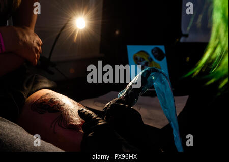 Skibbereen, West Cork, Ireland. 20th Oct, 2018. Sammi Ville from Cork tattos the leg of Lisa Timmis from Bantry during the tattoo show. The show has been attended by many tattooists from across Ireland and the North. The event finishes tomorrow. Credit: Andy Gibson/Alamy Live News. Stock Photo