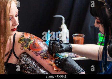 Skibbereen, West Cork, Ireland. 20th Oct, 2018. Tattooist Kat Paine from Belfast tattoos the arm of a show attendee. The show has been attended by many tattooists from across Ireland and the North. The event finishes tomorrow. Credit: Andy Gibson/Alamy Live News. Stock Photo