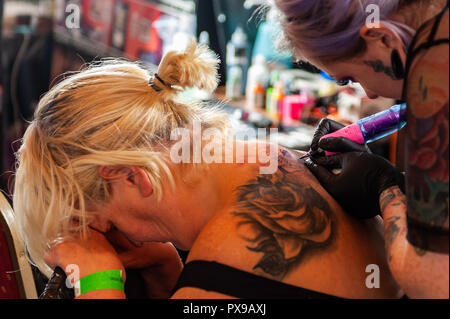 Skibbereen, West Cork, Ireland. 20th Oct, 2018. A customer finds it difficult to take the pain whilst having a tattoo done at the show. The show has been attended by many tattooists from across Ireland and the North. The event finishes tomorrow. Credit: Andy Gibson/Alamy Live News. Stock Photo