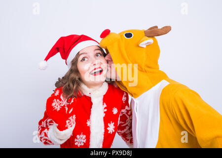 Happy young woman in santa claus hat and man in carnival costume of deer. Fun, holiday, joke and christmas concept Stock Photo