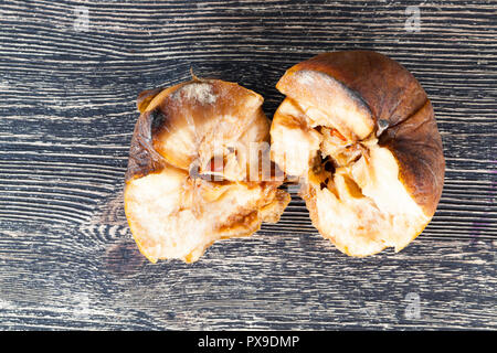 broken down half-rotten apple lying on a wooden table, closeup Stock Photo